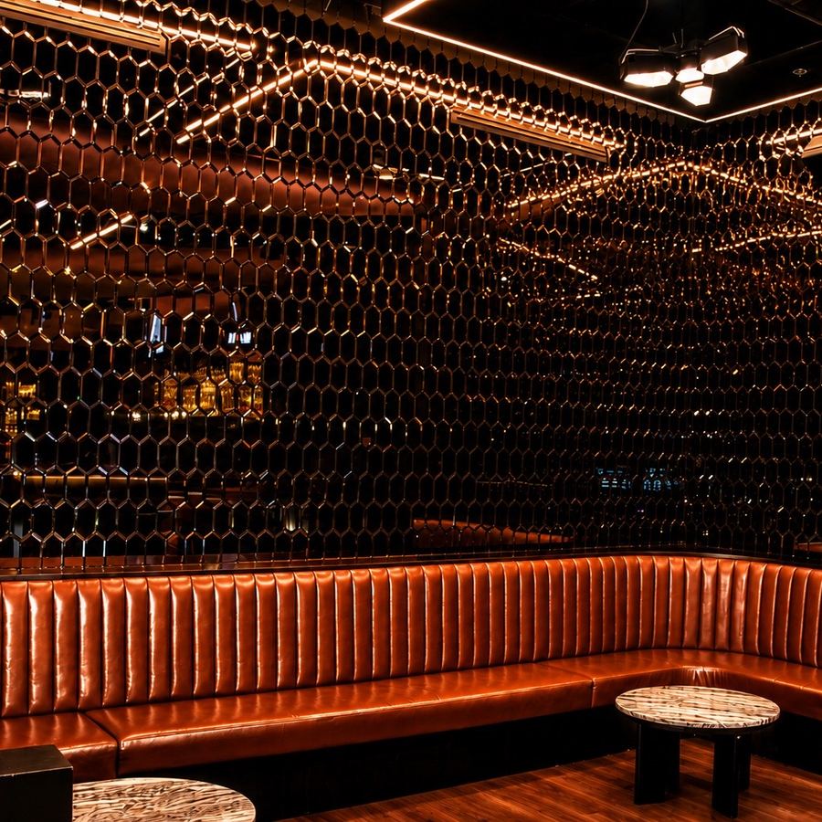 Channel-tufted leather booth beneath the chain-link ceiling installation
